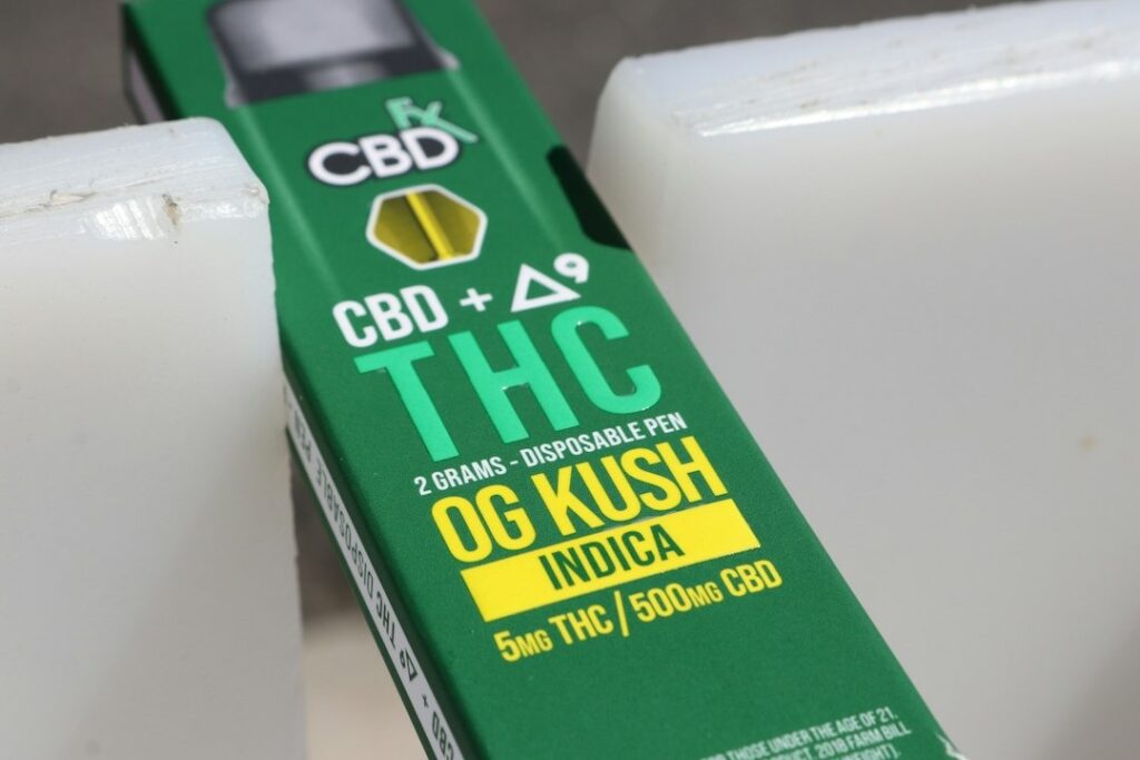 Green CBD + Delta-9 THC vape pen box between off-white blocks.